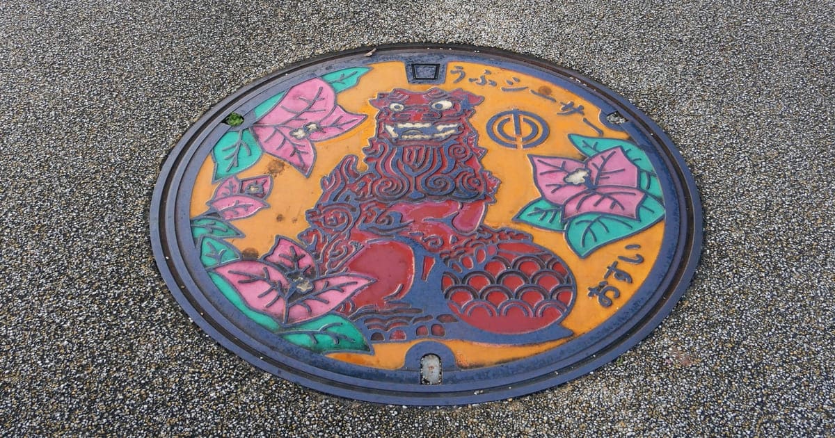 ハイビスカスの花と、赤いシーサーが描かれたカラーマンホールの写真